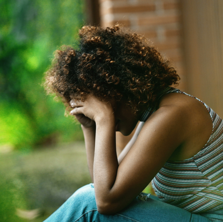 Woman sitting alone by a window, looking thoughtful—symbolizing emotional shutdown due to shame.